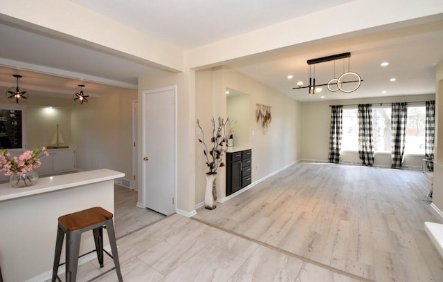 interior space featuring baseboards, open floor plan, light countertops, recessed lighting, and hanging light fixtures