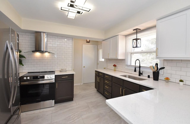 kitchen featuring appliances with stainless steel finishes, light countertops, wall chimney exhaust hood, and a sink