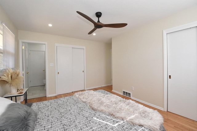 bedroom with visible vents, baseboards, light wood-style flooring, recessed lighting, and two closets