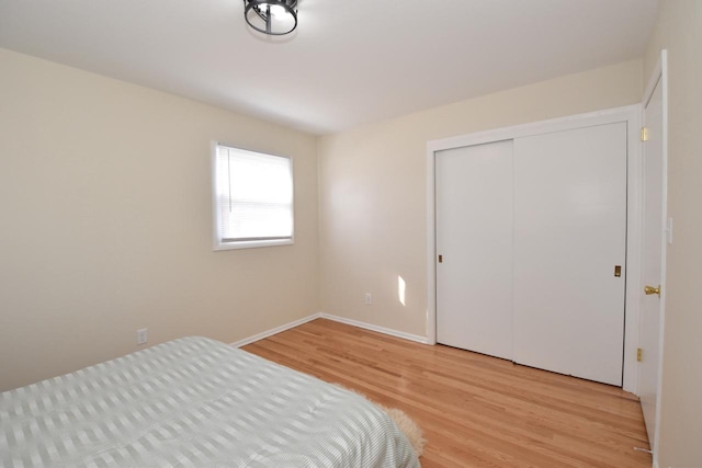 bedroom featuring a closet, baseboards, and light wood-style floors