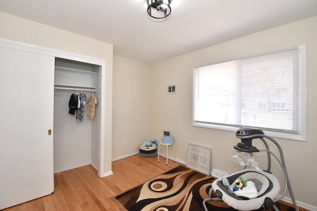 workout area featuring visible vents, light wood-style floors, and baseboards