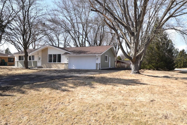 view of side of property featuring brick siding, driveway, and a yard