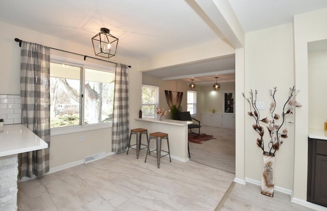 kitchen featuring visible vents, pendant lighting, a breakfast bar area, and light countertops