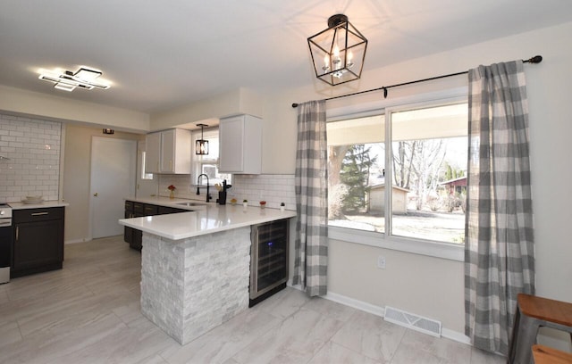 kitchen with light countertops, beverage cooler, visible vents, and a sink