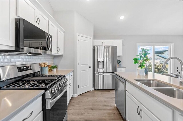 kitchen with a sink, light countertops, light wood finished floors, and stainless steel appliances