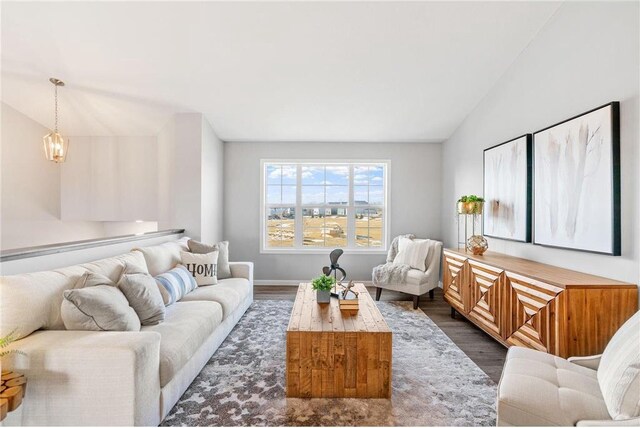 living room with baseboards, lofted ceiling, and dark wood-style floors