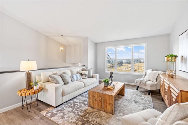 living room with vaulted ceiling, wood finished floors, and baseboards