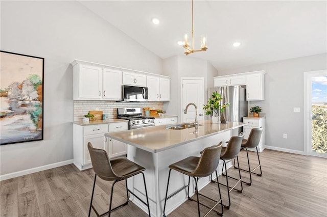 kitchen featuring a sink, light countertops, white cabinets, appliances with stainless steel finishes, and a kitchen bar