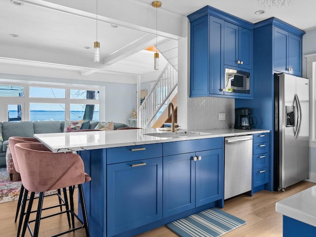 kitchen featuring a sink, blue cabinetry, appliances with stainless steel finishes, and open floor plan