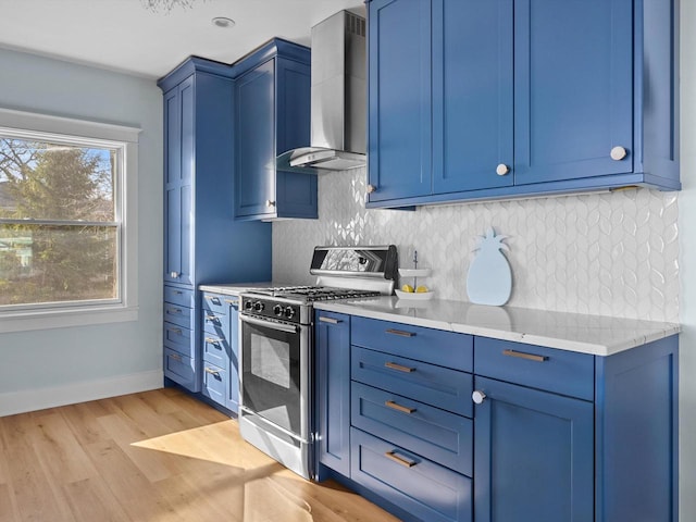 kitchen featuring wall chimney range hood, blue cabinets, and gas stove