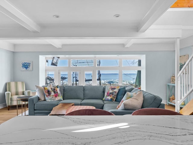 living area with stairway, plenty of natural light, beam ceiling, and light wood-style flooring