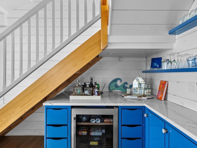 bar featuring a bar, wine cooler, wood finished floors, and wood walls