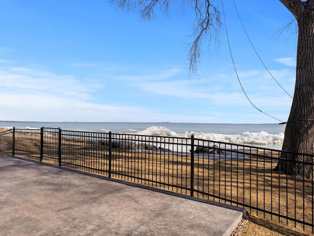 view of patio with fence and a water view