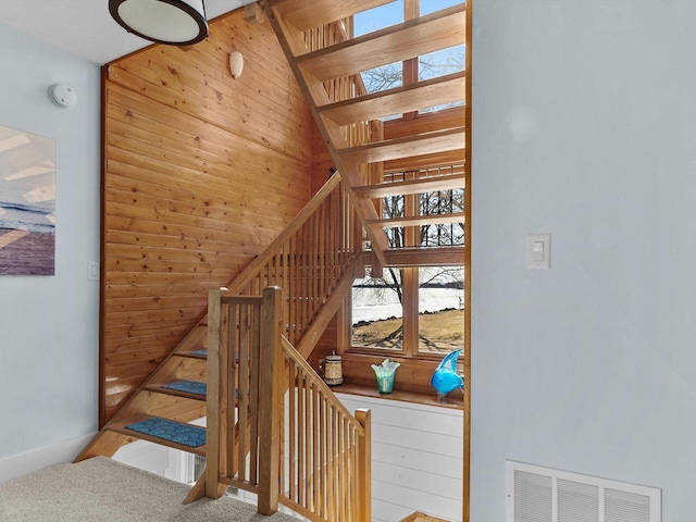 stairs featuring visible vents, wooden walls, and carpet flooring