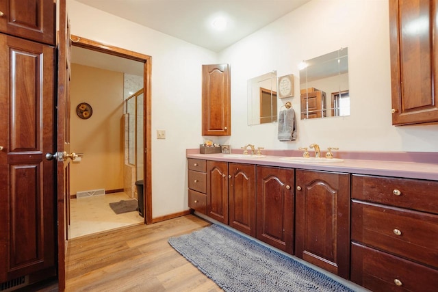 bathroom with a sink, visible vents, wood finished floors, and a shower stall