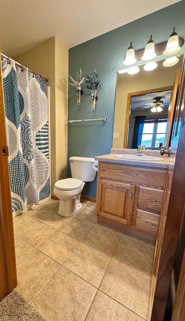 full bath with vanity, baseboards, tile patterned flooring, curtained shower, and toilet