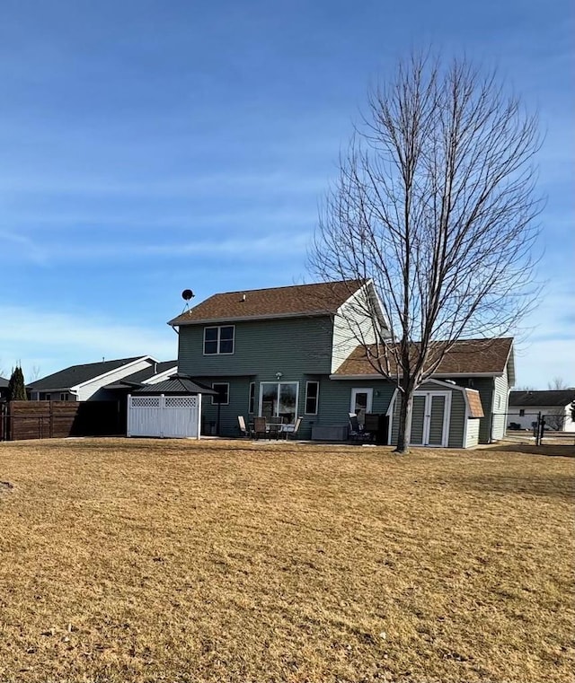 rear view of property with an outbuilding, a storage unit, fence, and a lawn