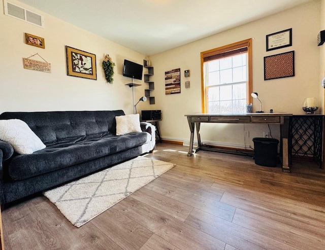 living area with wood finished floors, visible vents, and baseboards