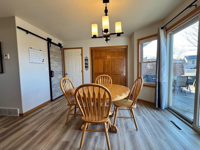 dining space with visible vents, light wood-style flooring, and a barn door