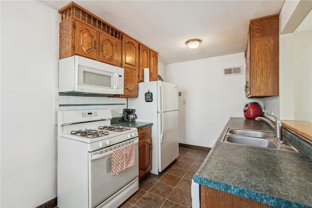 kitchen featuring white appliances, visible vents, a sink, decorative backsplash, and dark tile patterned floors