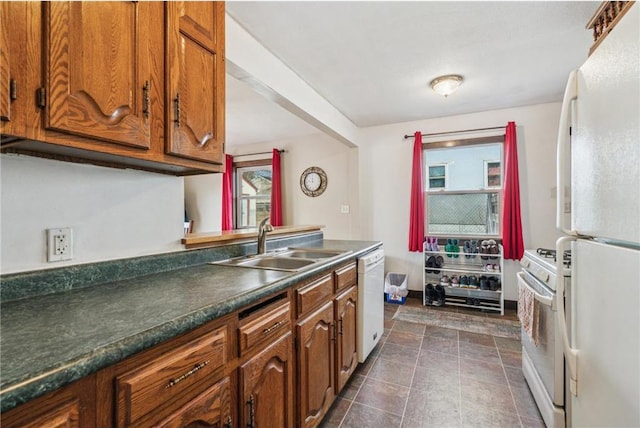 kitchen featuring a sink, white appliances, dark countertops, and brown cabinetry