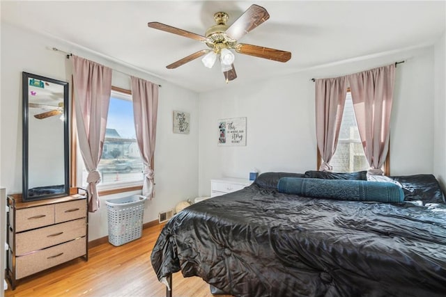 bedroom with visible vents, light wood-style flooring, a ceiling fan, and baseboards