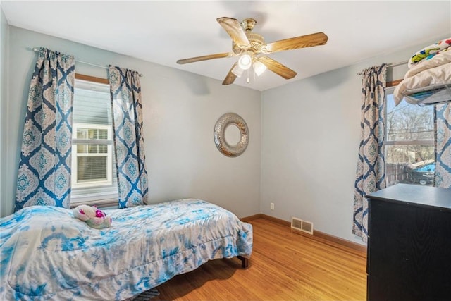 bedroom featuring visible vents, light wood-style flooring, baseboards, and ceiling fan