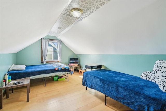 bedroom with lofted ceiling and wood finished floors