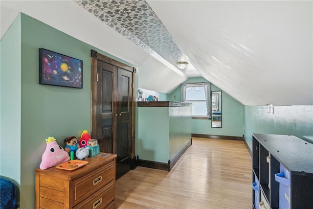 additional living space with light wood-type flooring, baseboards, and vaulted ceiling