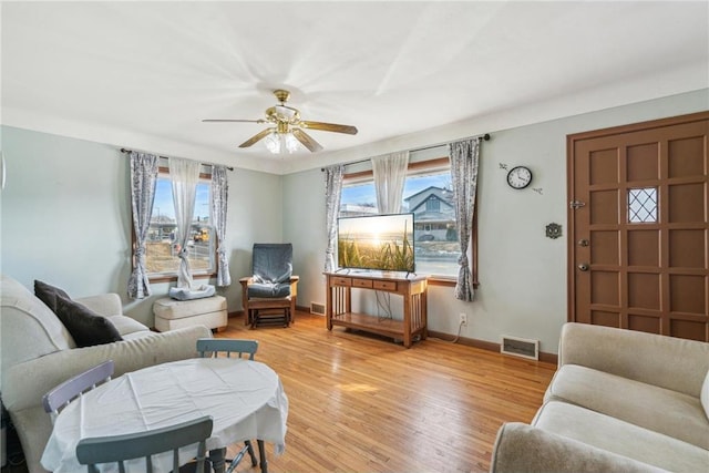 living area with baseboards, visible vents, light wood finished floors, and ceiling fan