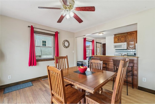 dining room featuring light wood-style floors, baseboards, and ceiling fan