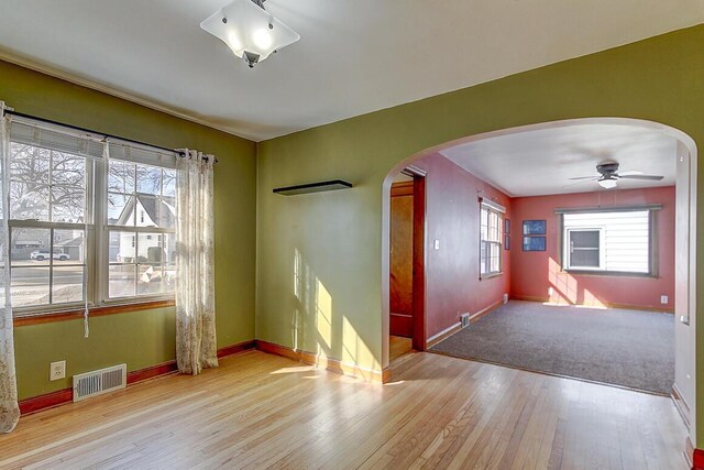 interior space featuring wood finished floors, arched walkways, visible vents, and baseboards