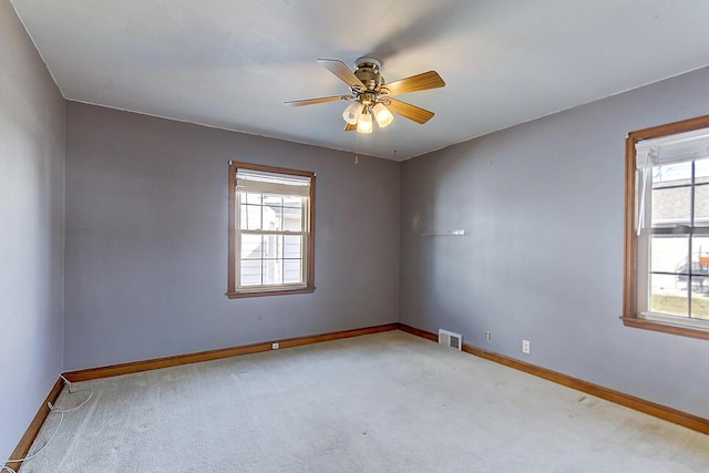 carpeted empty room featuring visible vents, baseboards, and ceiling fan