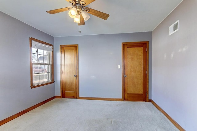 empty room featuring light carpet, visible vents, ceiling fan, and baseboards