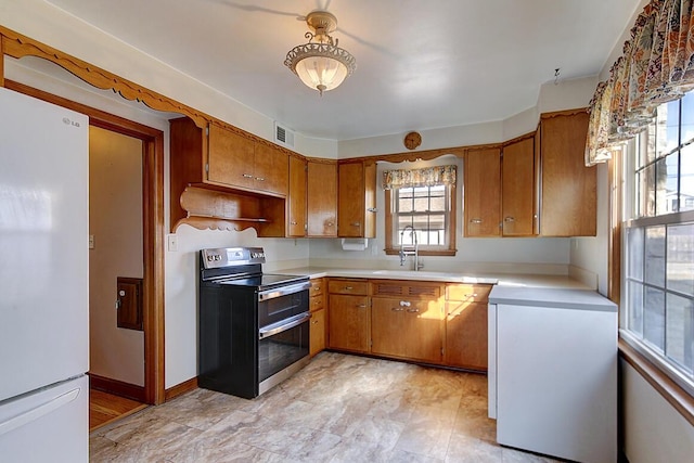 kitchen with a sink, double oven range, refrigerator, freestanding refrigerator, and light countertops