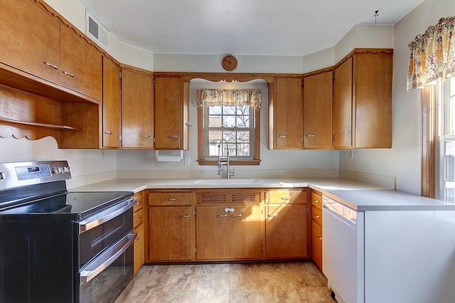 kitchen with a sink, light countertops, white dishwasher, and range with two ovens