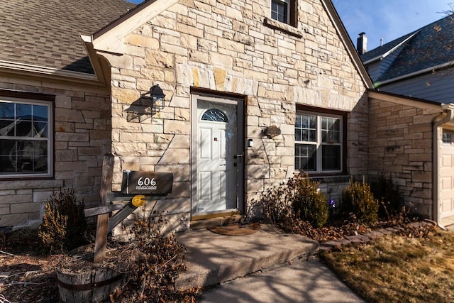 property entrance featuring stone siding and roof with shingles