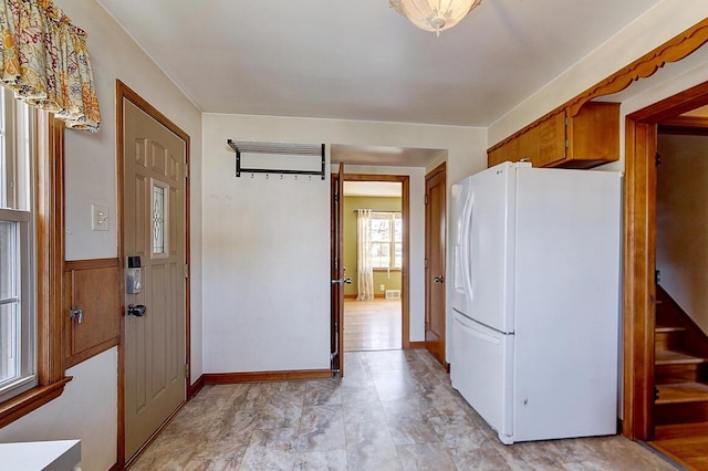 kitchen with brown cabinets, wainscoting, and freestanding refrigerator