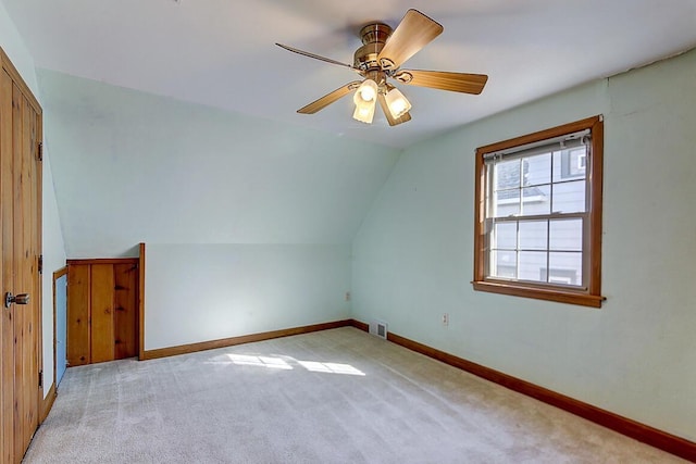 additional living space with lofted ceiling, baseboards, visible vents, and light carpet