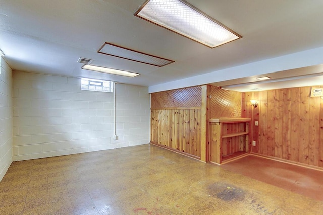 below grade area featuring tile patterned floors, wooden walls, concrete block wall, and visible vents