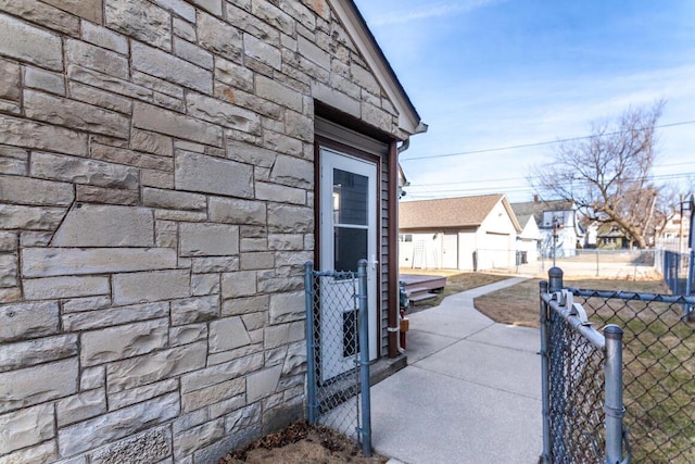 view of side of home featuring a gate, fence, and stone siding