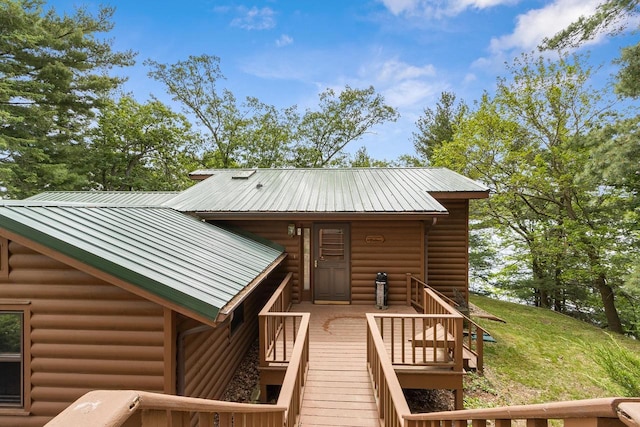 view of front of house with log veneer siding, metal roof, a wooden deck, and a front yard