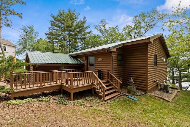 rear view of house featuring log veneer siding, a deck, central AC unit, and metal roof