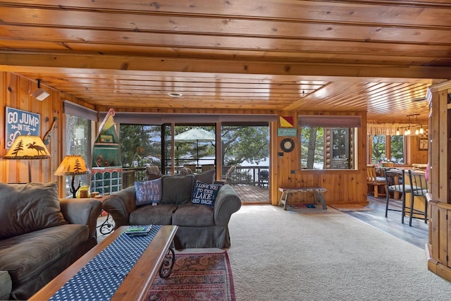 living area featuring a notable chandelier, wooden walls, wood ceiling, and carpet