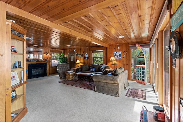 living area with wood walls, a fireplace, wood ceiling, and carpet floors