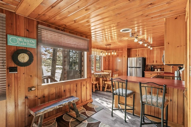 kitchen with wooden walls, appliances with stainless steel finishes, wooden ceiling, and a sink