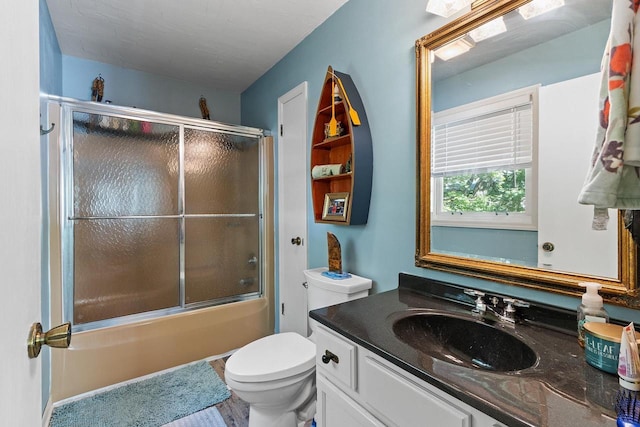 bathroom featuring combined bath / shower with glass door, toilet, and vanity