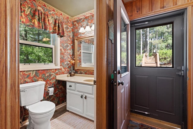 bathroom featuring plenty of natural light, toilet, wallpapered walls, and vanity