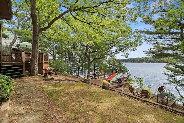 view of yard featuring stairway and a deck with water view