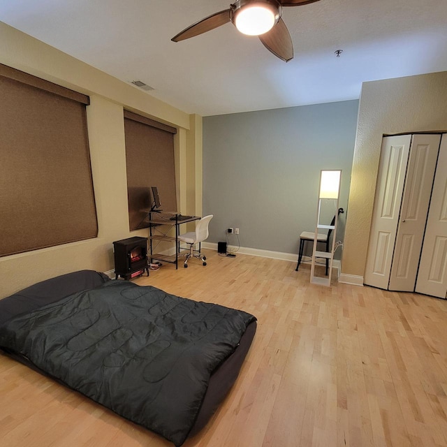 bedroom with a ceiling fan, wood finished floors, visible vents, and baseboards